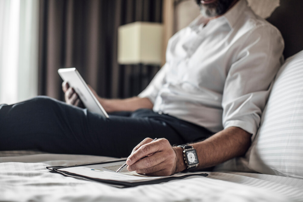 A businessman on a hotel bed using a table.