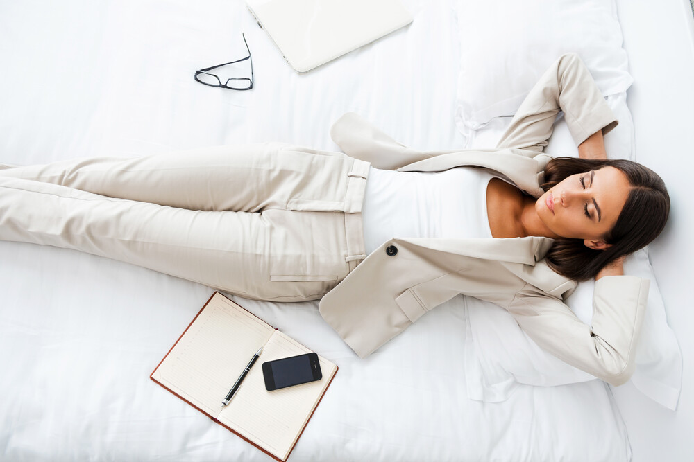 A young businesswoman resting on a hotel bed.